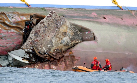 Firefighters on a dinghy examine a large rock emerging from the side of the luxury cruise ship Costa Concordia, the day after it ran aground on Sunday, January 15, 2012. (AP Photo/Andrea Sinibaldi, Lapresse)
